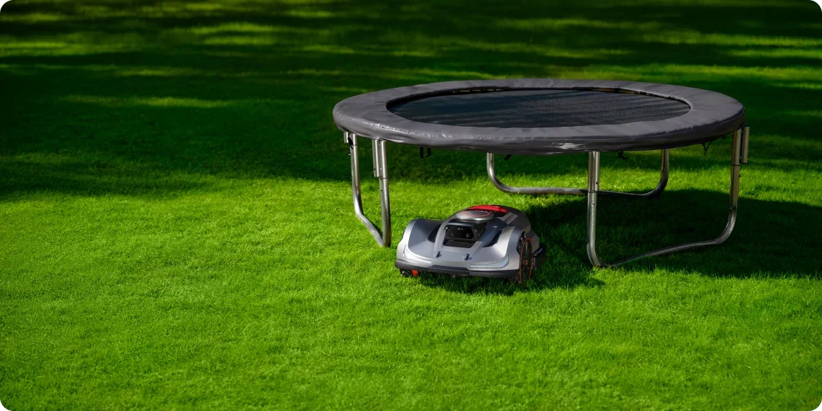 Mähroboter mäht unter einem Trampolin